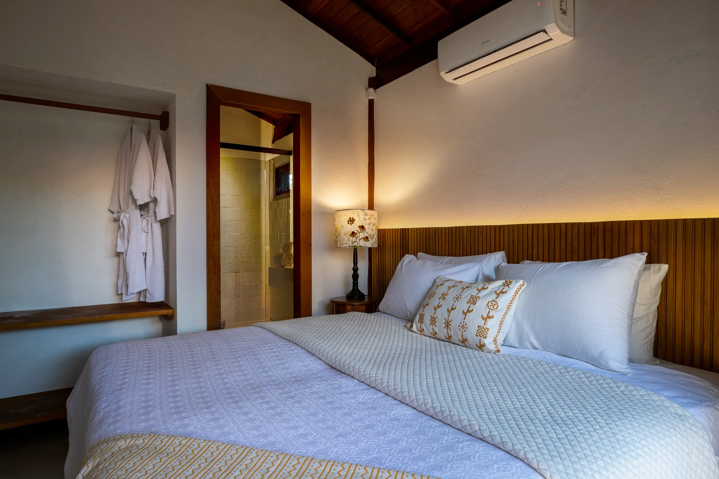 Quarto com cama king, roupões pendurados e luz indireta