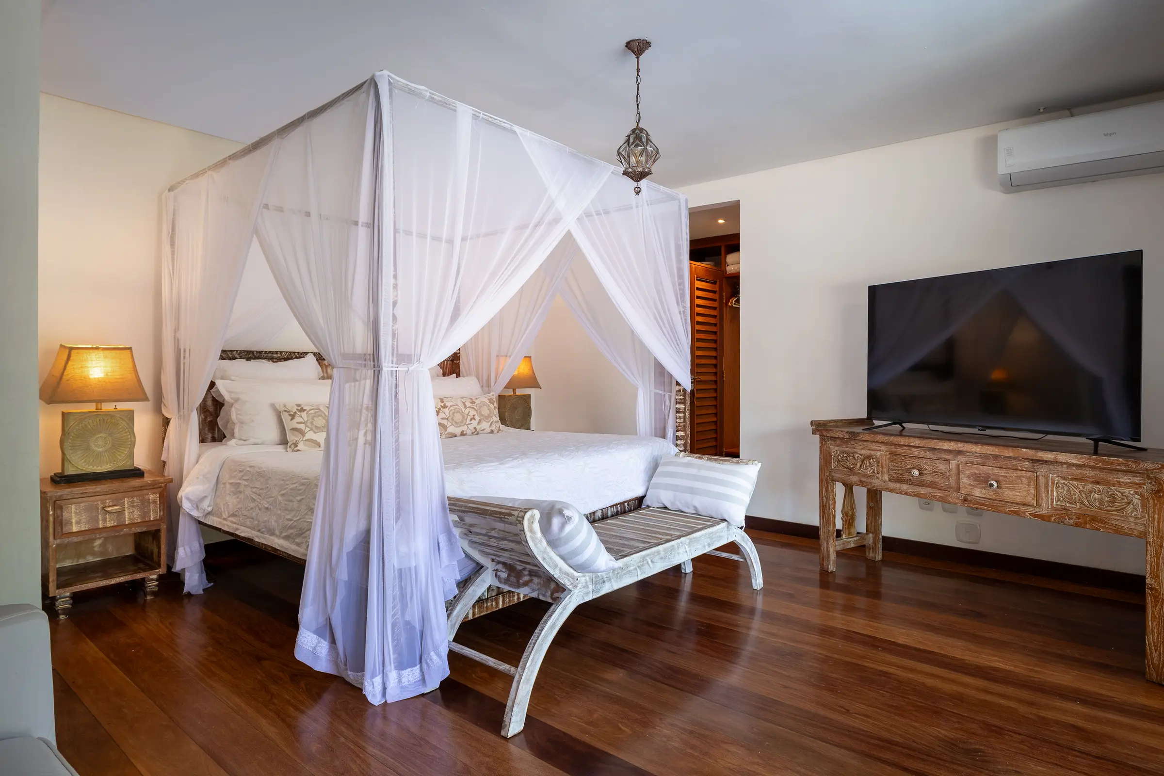 Quarto com cama de dossel e mosquiteiro branco, piso de madeira