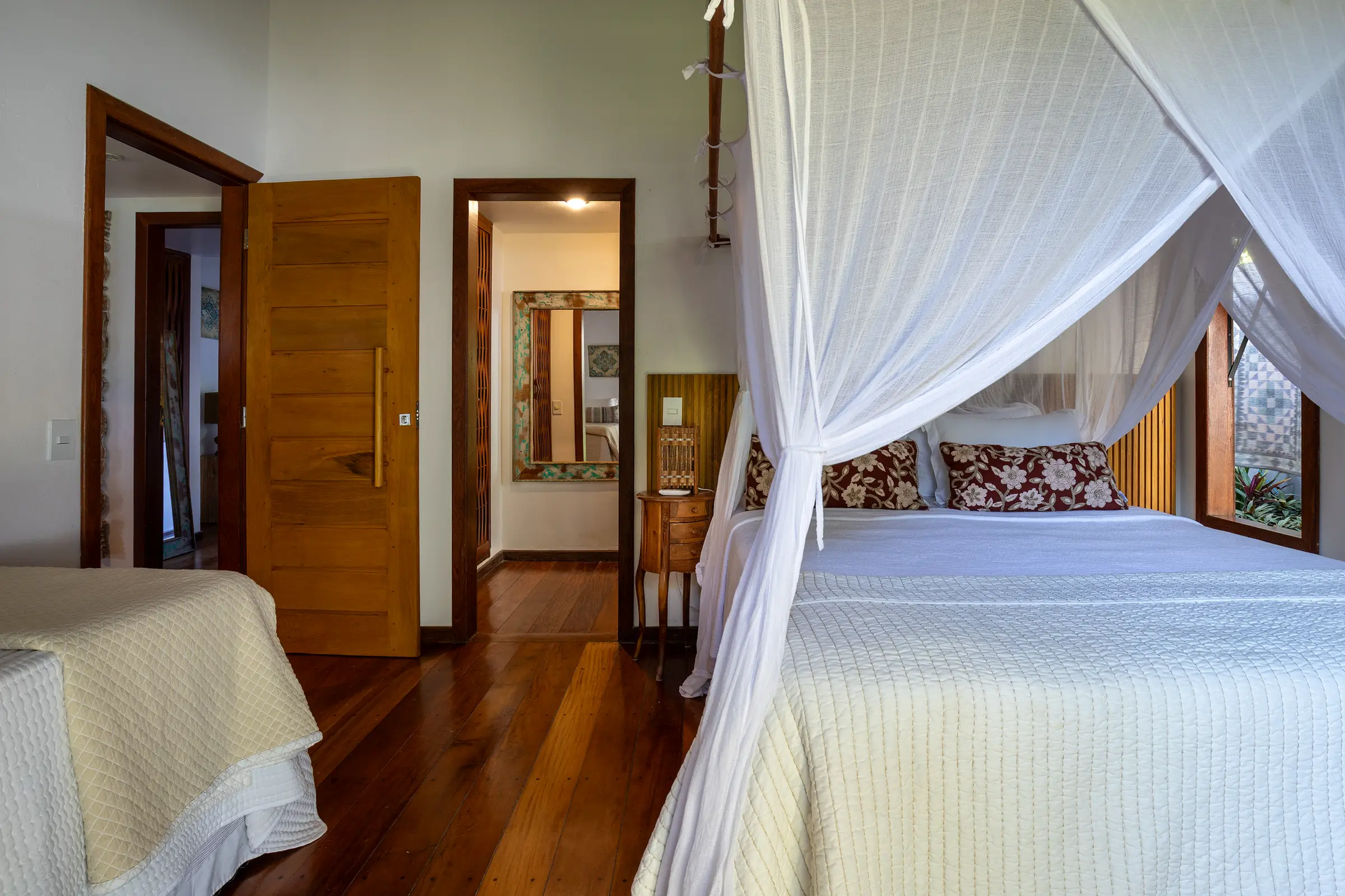 Quarto com cama de dossel e portas de madeira para o banheiro