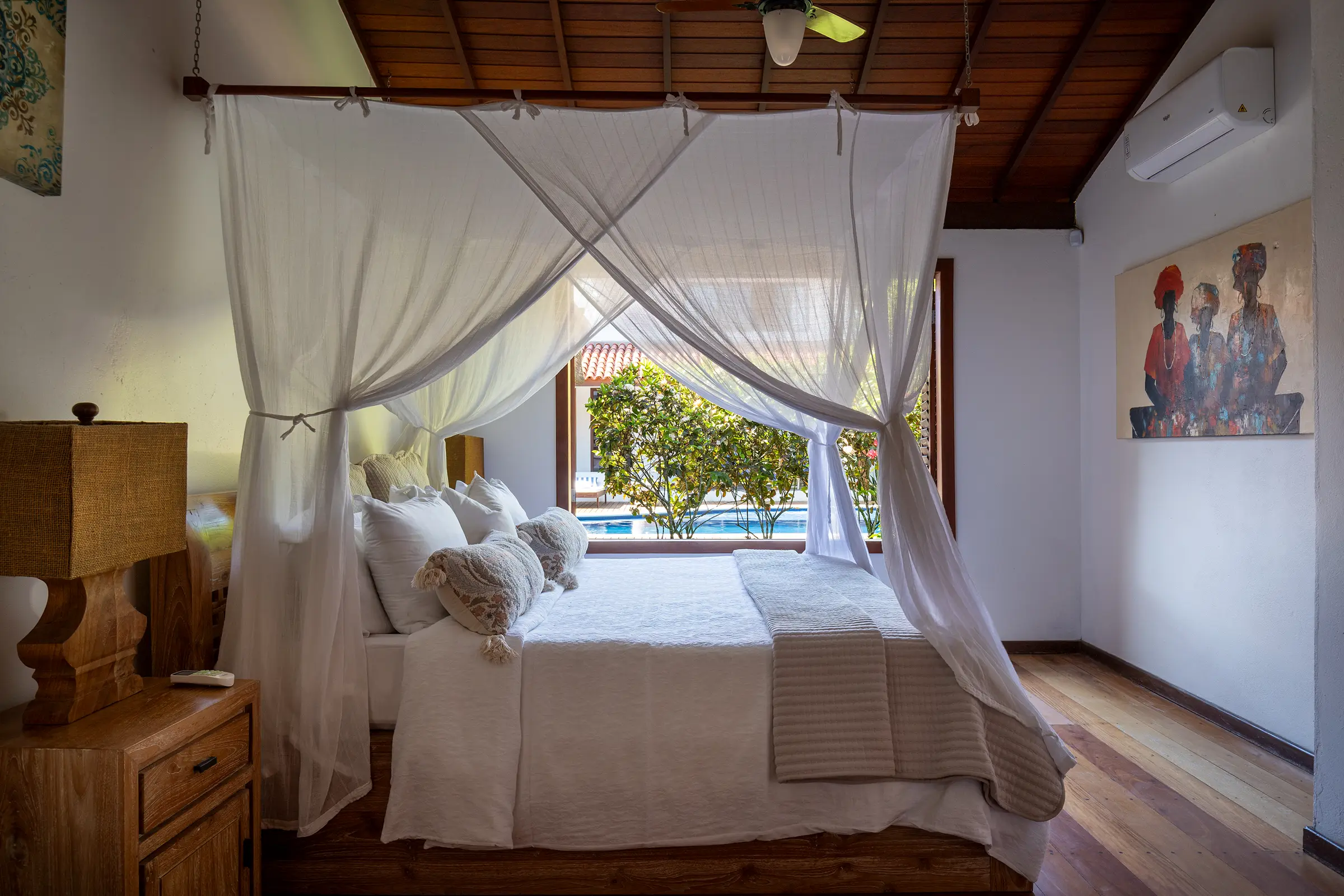 Quarto com cama de dossel e vista para a piscina