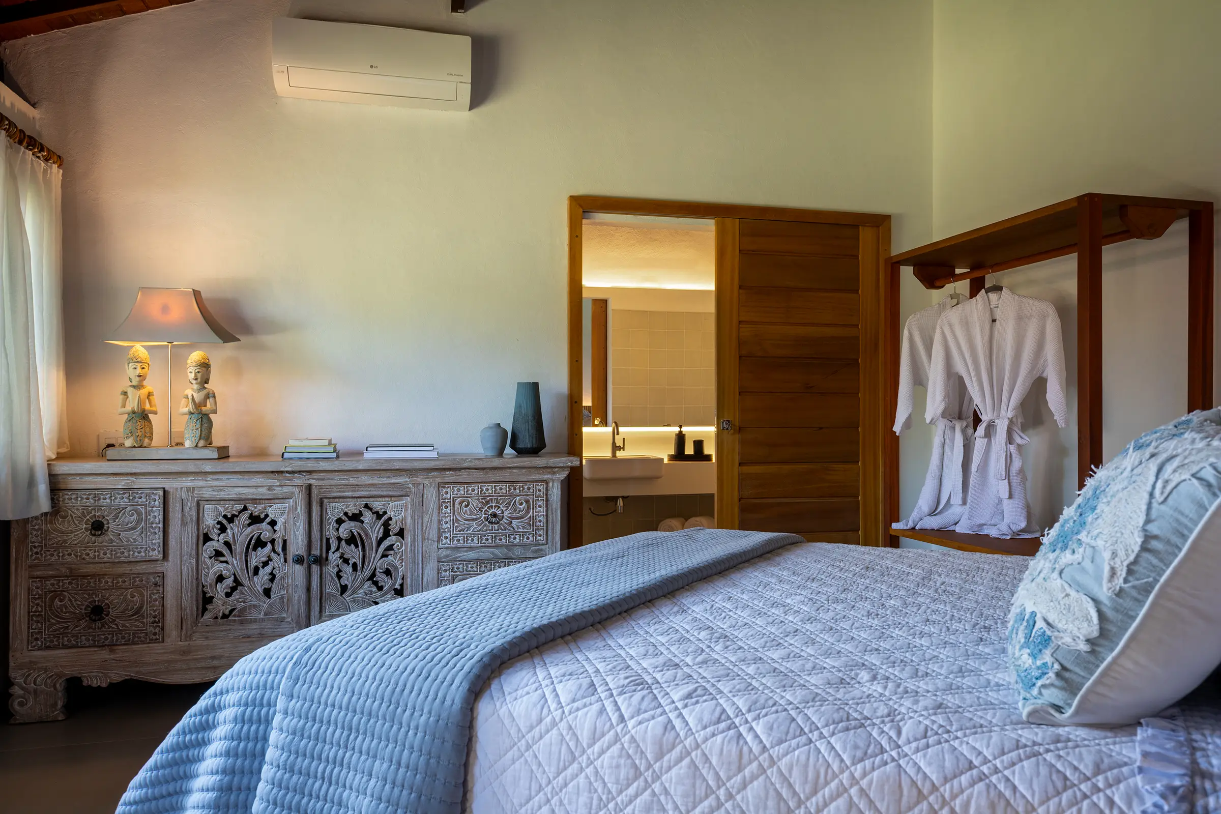 Quarto com cômoda entalhada, roupa de cama azul e roupões