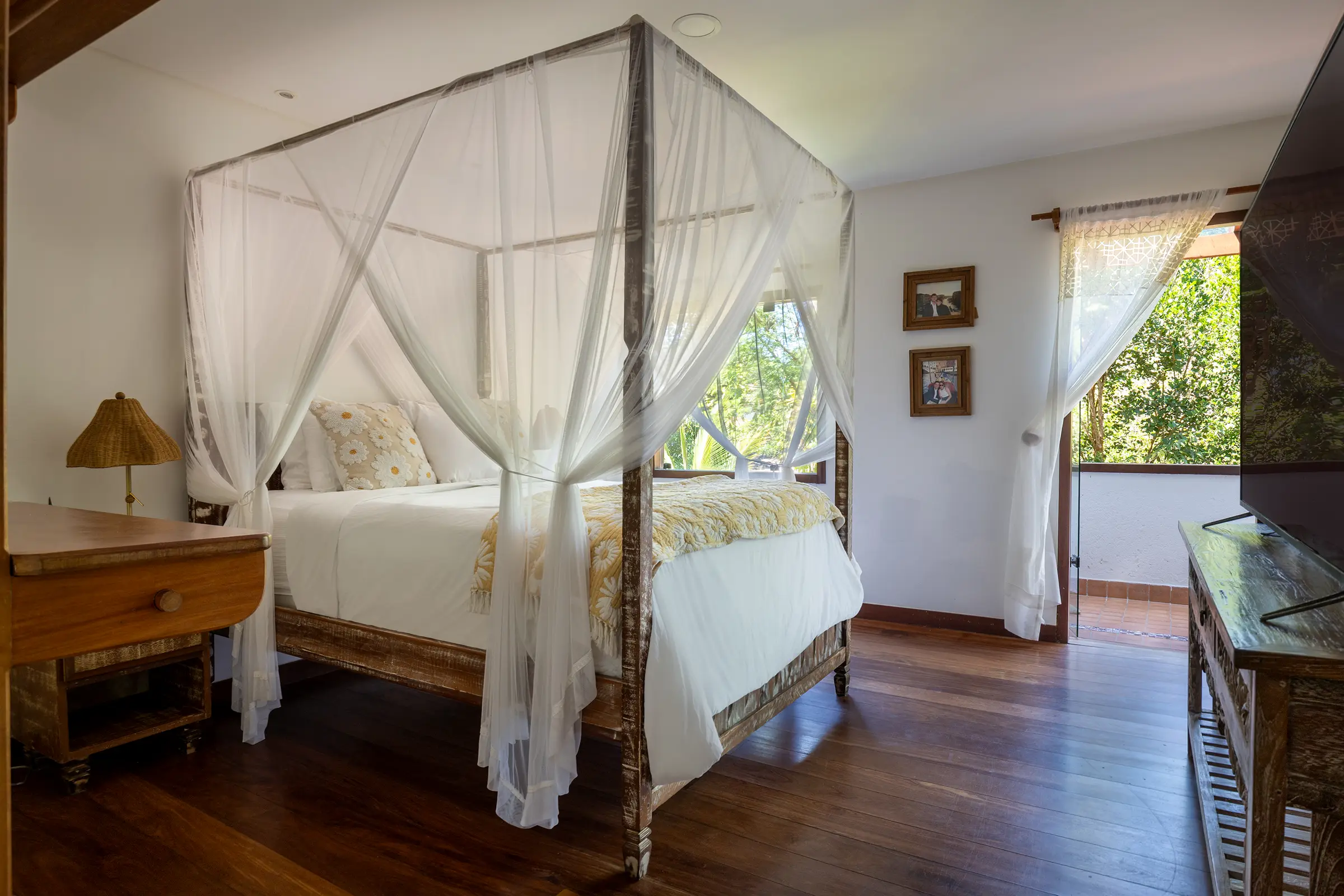 Quarto com cama de dossel de madeira e janela para o verde