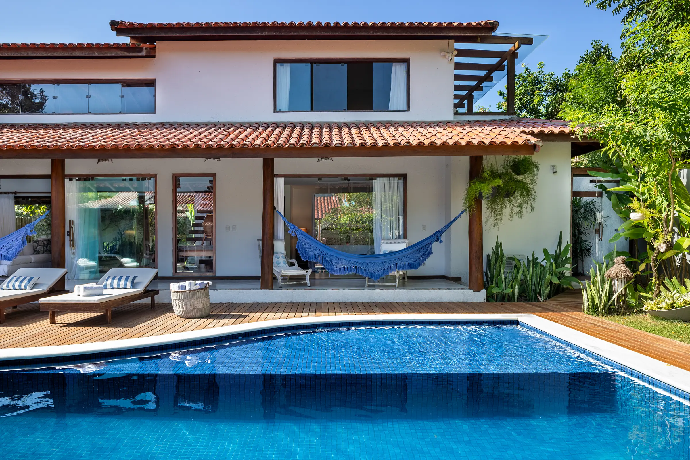 Fachada de dois pavimentos com varanda e redes sobre o deck da piscina