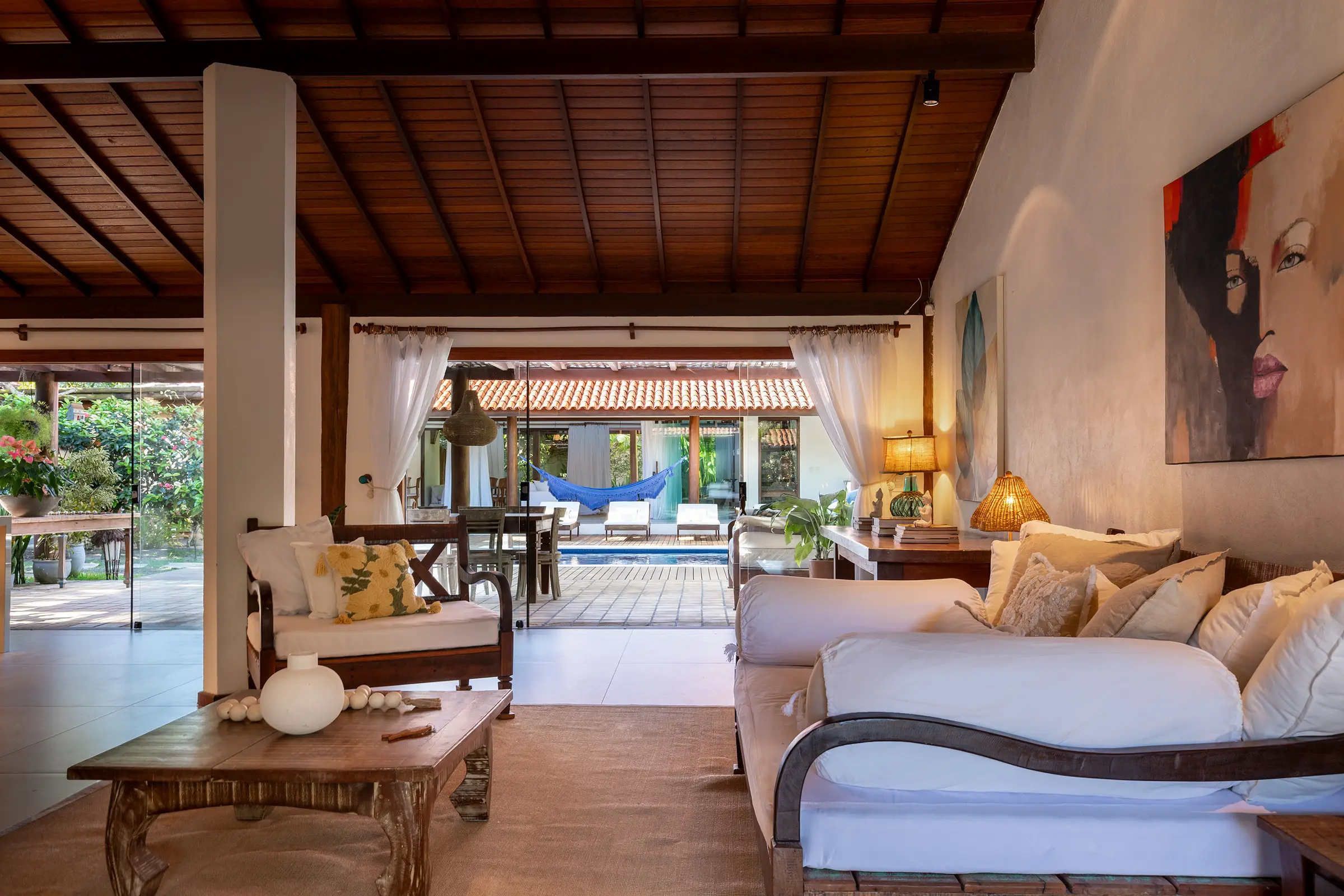 Sala com sofás claros, arte na parede e vista para a varanda e a piscina