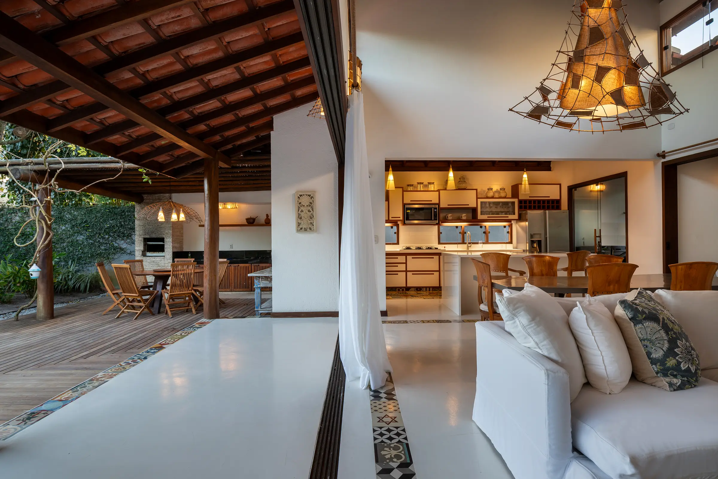 Sala com sofá branco aberta para o deck e a área gourmet