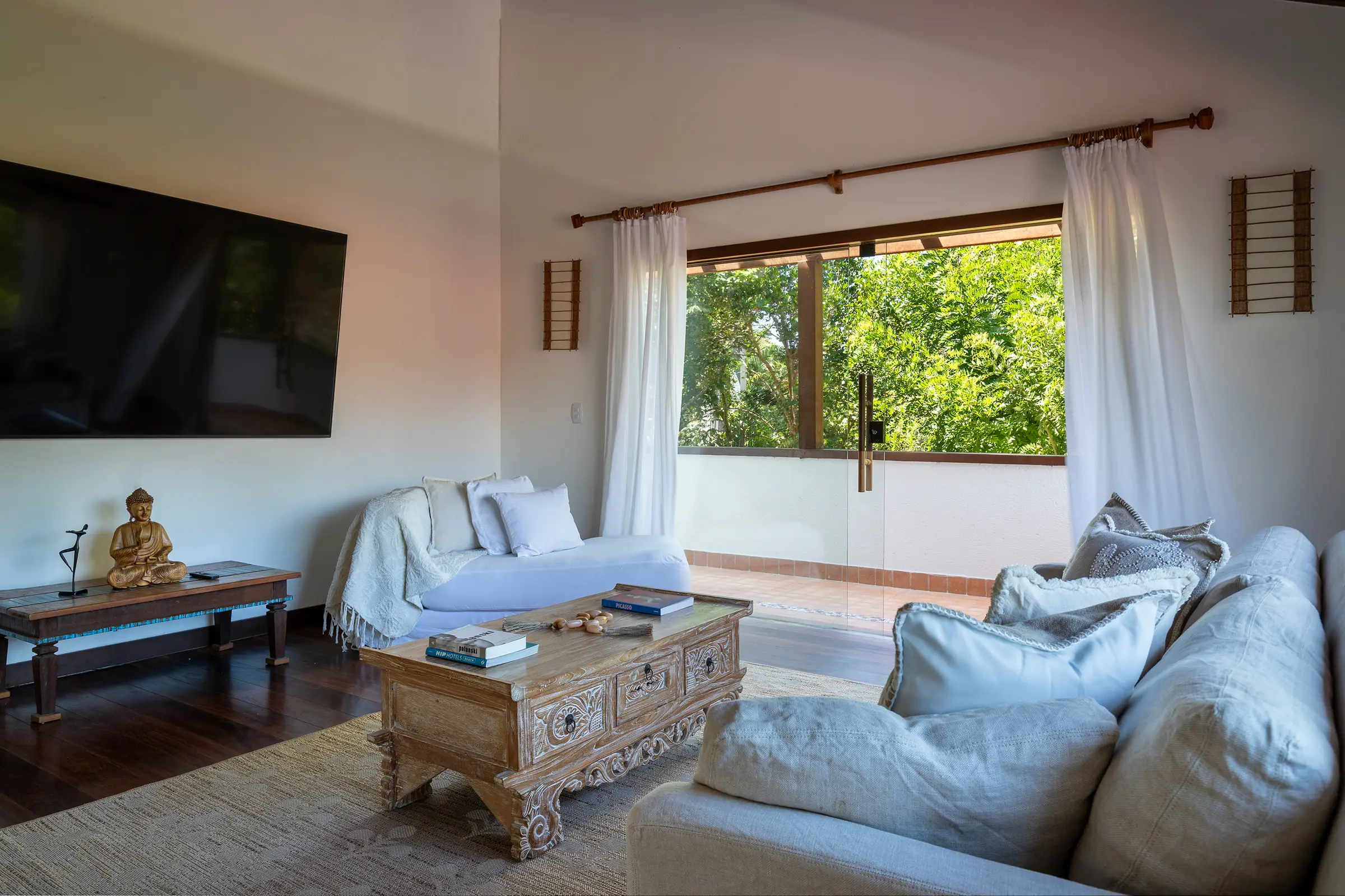 Sala de TV com sofá claro e janela para o jardim